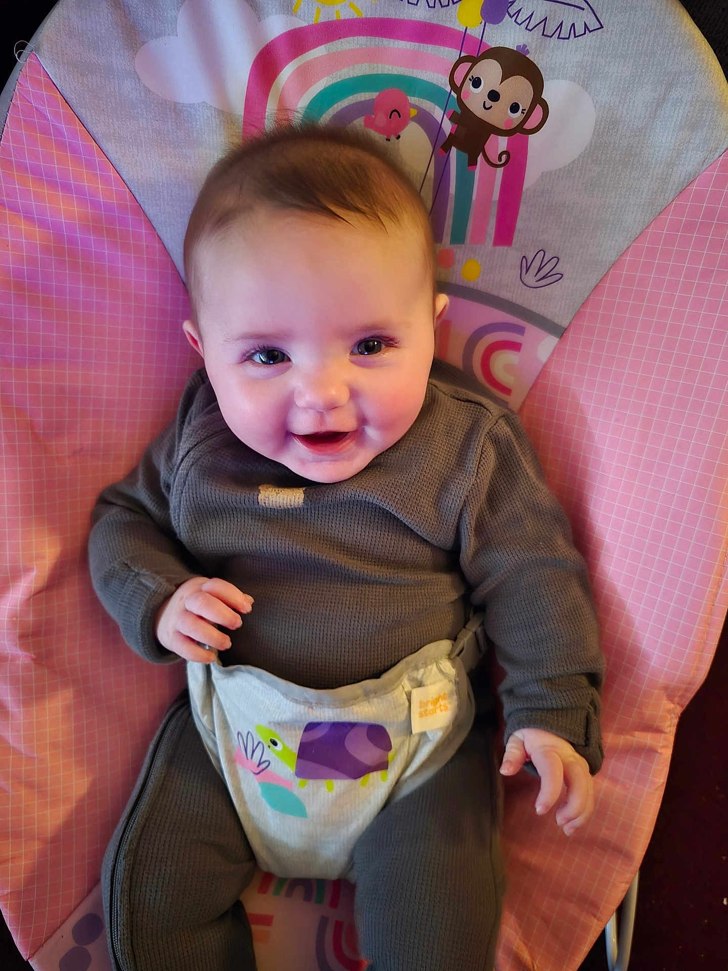 Amelia is registered to the contest to win money with this photo: baby, infant, smile, child, baby_chair, clothing, cute, happy, indoor, person, face, head, seat, toddler, colorful, pattern, monkey, rainbow, comfort, portrait