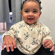 Thiare is registered to the contest to win money with this photo: toddler, child, smiling, happy, sweater, patterned_clothing, hands, sitting, indoors, portrait, cute, baby, face, black_hair, long_sleeves, playful, cozy, young_child, expression, close_up