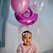 Thiare is registered to the contest to win money with this photo: baby, balloon, bed, celebration, child, cute, decor, festive, happy, headband, indoor, infant, number_balloon, pink_sweater, portrait, sitting, smile, toy, white_headband, young_child