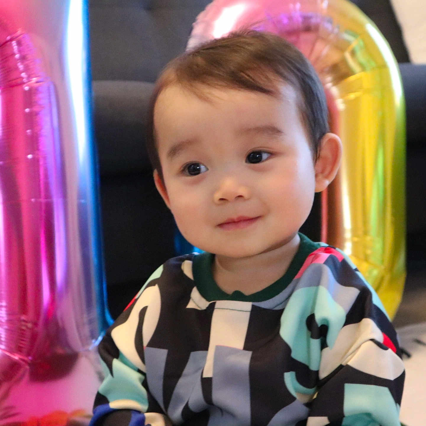 Kingsley joined the competition — help win amazing prizes! toddler, child, face, balloon, colorful, indoor, celebration, patterned_clothing, curly_hair, smiling, young_child, portrait, sitting, bright_colors, decorations, happy, cute, baby, head, casual