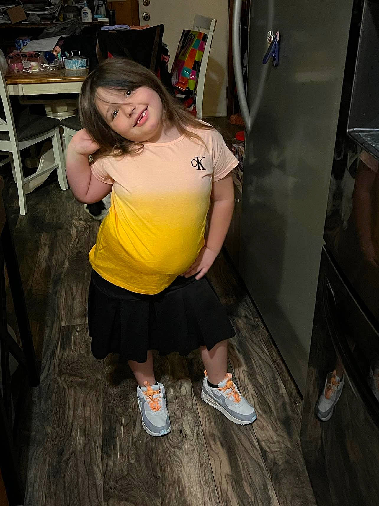 Jaimee is registered to the contest to win money with this photo: black_hair, calf, chair, chest, elbow, flooring, footwear, fun, human_leg, joy, knee, leg, leisure, person, room, sandal, sneakers, sportswear, table, thigh