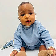 Hakim participe au concours pour gagner de l'argent avec cette photo : baby, blue_sweater, booties, child, clothing, curious_expression, cute, eyes, face, feet, hands, indoor, infant, portrait, sitting, skin, soft_lighting, table_surface, toddler, white_background