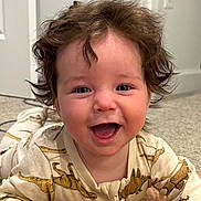 Mary Grace joined the competition — help win amazing prizes! baby, child, smile, happy, curly_hair, blue_eyes, onesie, dinosaur_print, carpet, indoor, face, portrait, cute, toddler, baby_clothes, infant, expression, young_child, crawling, playful