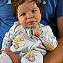 baby, child, person, onesie, bow, blue_eyes, facial_expression, hand, arm, clothing, adult, watch, sitting, closeup, cute, indoor, skin, hair, fabric, holding