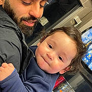 Yasser Aylan a rejoint le concours — aidez-le/la à gagner de superbes lots ! baby, man, adult_male, beard, smile, cuddling, jacket, window, soda_cans, beverages, indoor, public_transport, holding, close_up, cute, curly_hair, cheeks, face, portrait, candid