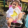 toddler, child, outdoor, chair, pink_chair, white_cardigan, yellow_outfit, sneakers, hair_clips, butterfly_clips, gravel, grass, daylight, cute, smiling, curious, small_chair, baby, person, casual_clothing