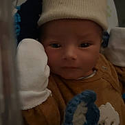 Kelyan a rejoint le concours — aidez-le/la à gagner de superbes lots ! newborn, baby, infant, hat, mitten, blanket, crocheted, brown_clothing, face, portrait, indoors, resting, cute, child, sleepwear, closeup, soft_texture, warm, cozy, baby_bed