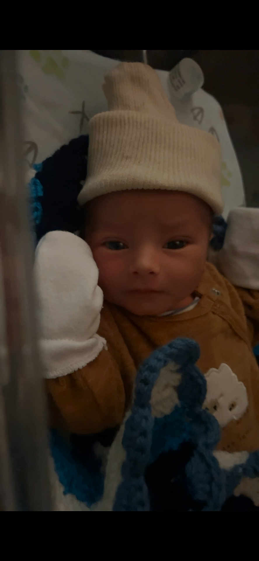 Kelyan a rejoint le concours — aidez-le/la à gagner de superbes lots ! newborn, baby, infant, hat, mitten, blanket, crocheted, brown_clothing, face, portrait, indoors, resting, cute, child, sleepwear, closeup, soft_texture, warm, cozy, baby_bed