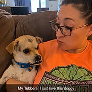 Tubbs joined the competition — help win amazing prizes! woman, dog, couch, indoor, glasses, orange_shirt, pet, living_room, ceiling_fan, window, brown_couch, casual, holding_pet, short_hair, funny_face, collar, small_dog, home_interior, person, playful