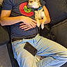 man, dog, couch, sleeping, relaxation, indoor, casual_clothing, pet, companion, rest, blue_jeans, tshirt, blanket, pillows, floor, light, comfort, home, nap, small_dog