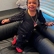Ophelia is registered to the contest to win money with this photo: toddler, child, smiling, black_clothing, red_shoes, leather_couch, plush_toy, elephant_plush, indoors, window_blinds, hair_beads, necklace, cute, happy, standing, person, home, casual, portrait, fashion