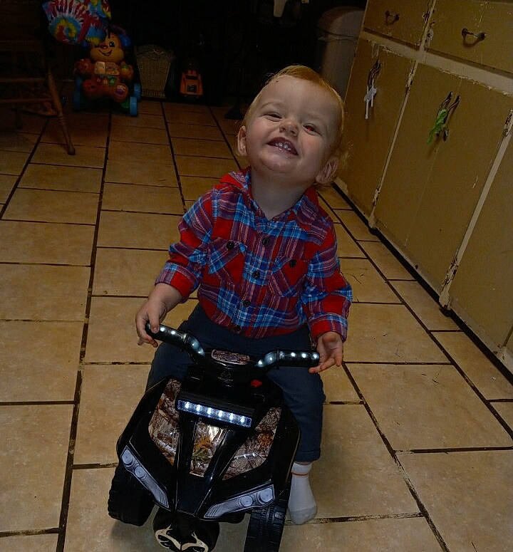 Ace is registered to the contest to win money with this photo: baby, baby_carriage, baby_products, baby_toddler_clothing, child, floor, flooring, fun, hardwood, joy, lap, pattern, person, plaid, product, rolling, sitting, smile, tartan, toddler