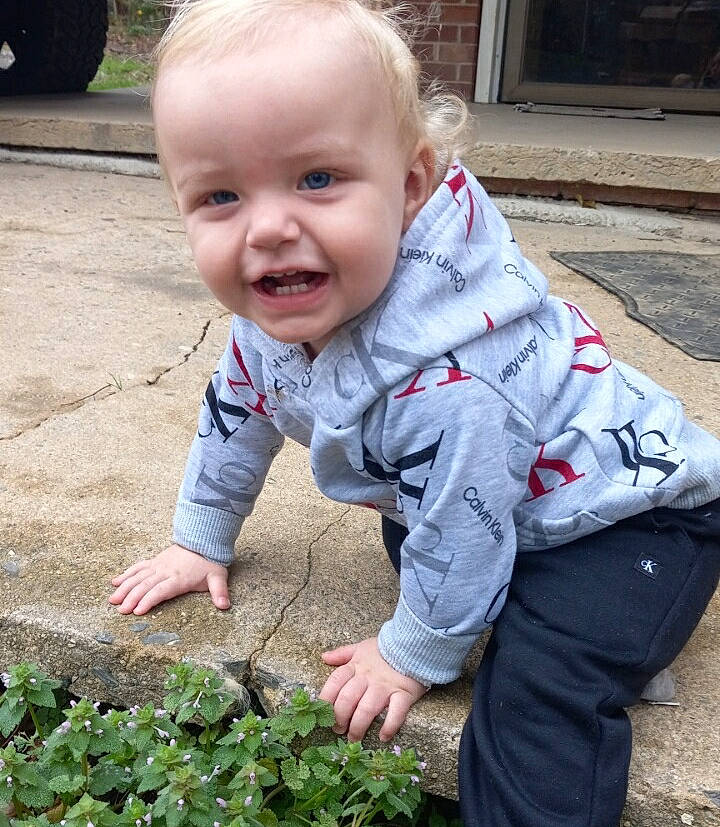 Ace is registered to the contest to win money with this photo: agriculture, baby, baby_toddler_clothing, child, face, garden, gardening, grass, groundcover, hand, happy, leaf, leaf_vegetable, people_in_nature, person, plant, plantation, sitting, smile, soil