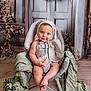 baby, child, bunny_ears, wicker_chair, butterfly_toy, flower_arrangement, green_fabric, portrait, indoor, cute, smiling, costume, toddler, decor, soft_lighting, seated, playful, infant, adorable, photography