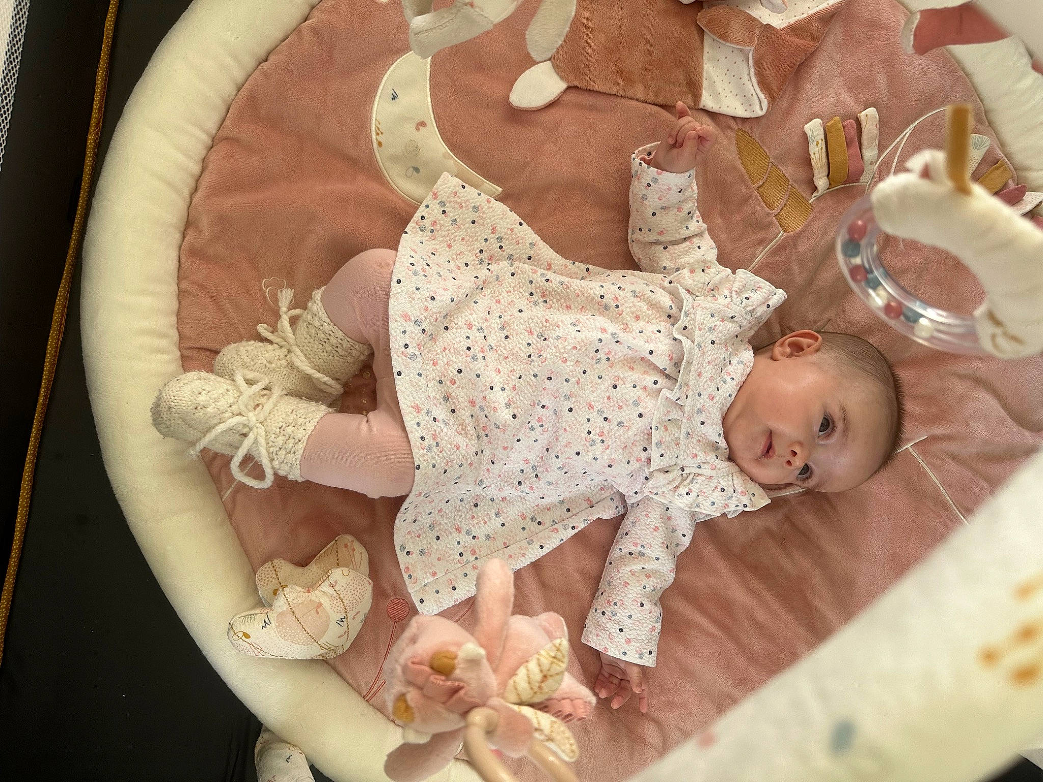 Malia a rejoint le concours — aidez-le/la à gagner de superbes lots ! baby, baby_products, baby_safety, baby_sleeping, baby_toddler_clothing, child, circle, comfort, flooring, hair_accessory, happy, infant_bed, linens, pattern, peach, person, petal, room, sitting, toddler