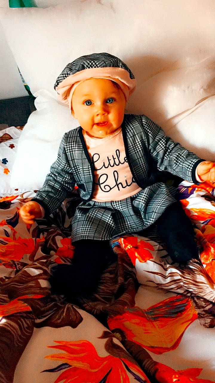 Shaily a rejoint le concours — aidez-le/la à gagner de superbes lots ! baby, baby_products, baby_toddler_clothing, cap, child, costume_hat, doll, fashion_accessory, fur, headwear, jewellery, knit_cap, orange, pattern, person, personal_protective_equipment, plaid, sitting, sleeve, tartan