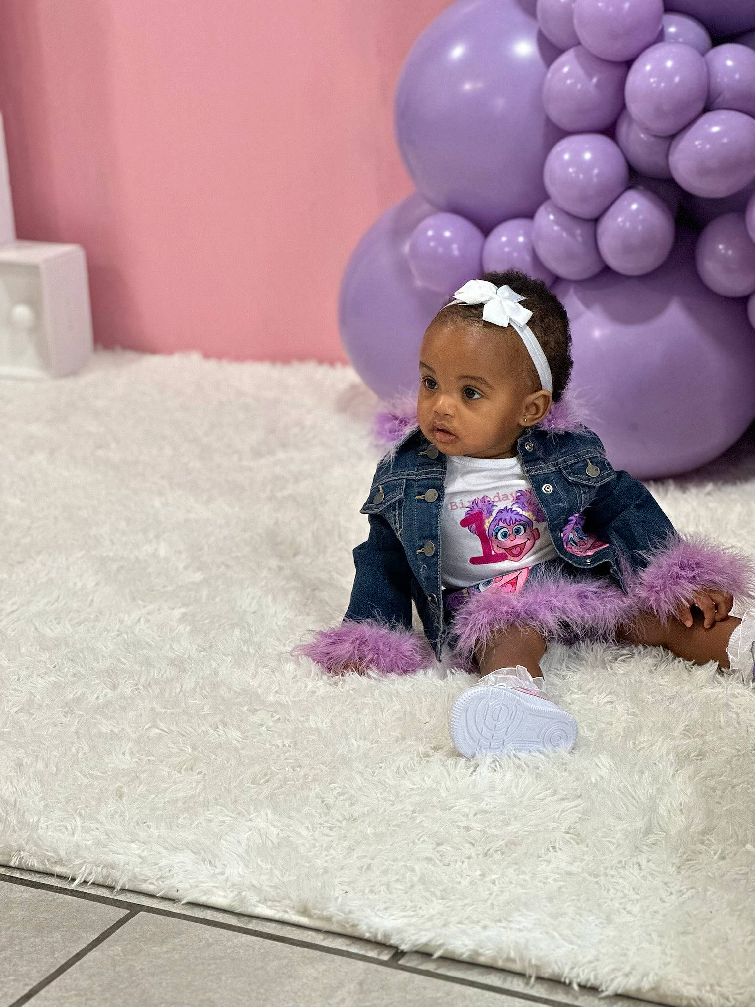 Mila is registered to the contest to win money with this photo: baby, baby_toddler_clothing, balloon, child, doll, fashion_accessory, flooring, fun, fur, happy, linens, magenta, paper_towel, party_supply, person, pink, play, purple, room, sitting