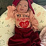 baby, infant, child, tongue_out, headband, bow, pillow, couch, blanket, valentine_shirt, heart, red, pink, clothing, onesie, skirt, portrait, cute, indoor, smile
