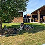 Vito participe au concours pour gagner de l'argent avec cette photo : dog, grass, tree, garden, statue, shed, outdoor_furniture, patio, sunny, blue_sky, relaxed, tongue_out, backyard, wooden_shed, lawn, shade, pet, canine, summer, nature