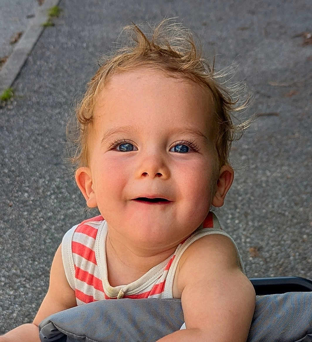 Léandre participe au concours pour gagner de l'argent avec cette photo : toddler, child, smiling, face, blue_eyes, hair, outdoor, pavement, striped_clothing, sleeveless, cute, happy, baby, person, portrait, skin, cheeks, daylight, casual, curious