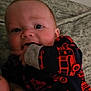 Dakota is registered to the contest to win money with this photo: baby, infant, child, face, hand, clothing, pattern, red, black, blanket, cute, chewing, closeup, indoors, person, young, soft, texture, sleepwear, portrait