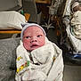 Dakota is registered to the contest to win money with this photo: baby, newborn, hospital, blanket, hat, medical_equipment, bed, person, infant, patient, care, swaddled, gaze, room, chair, adult, resting, tired, healthcare, closeup