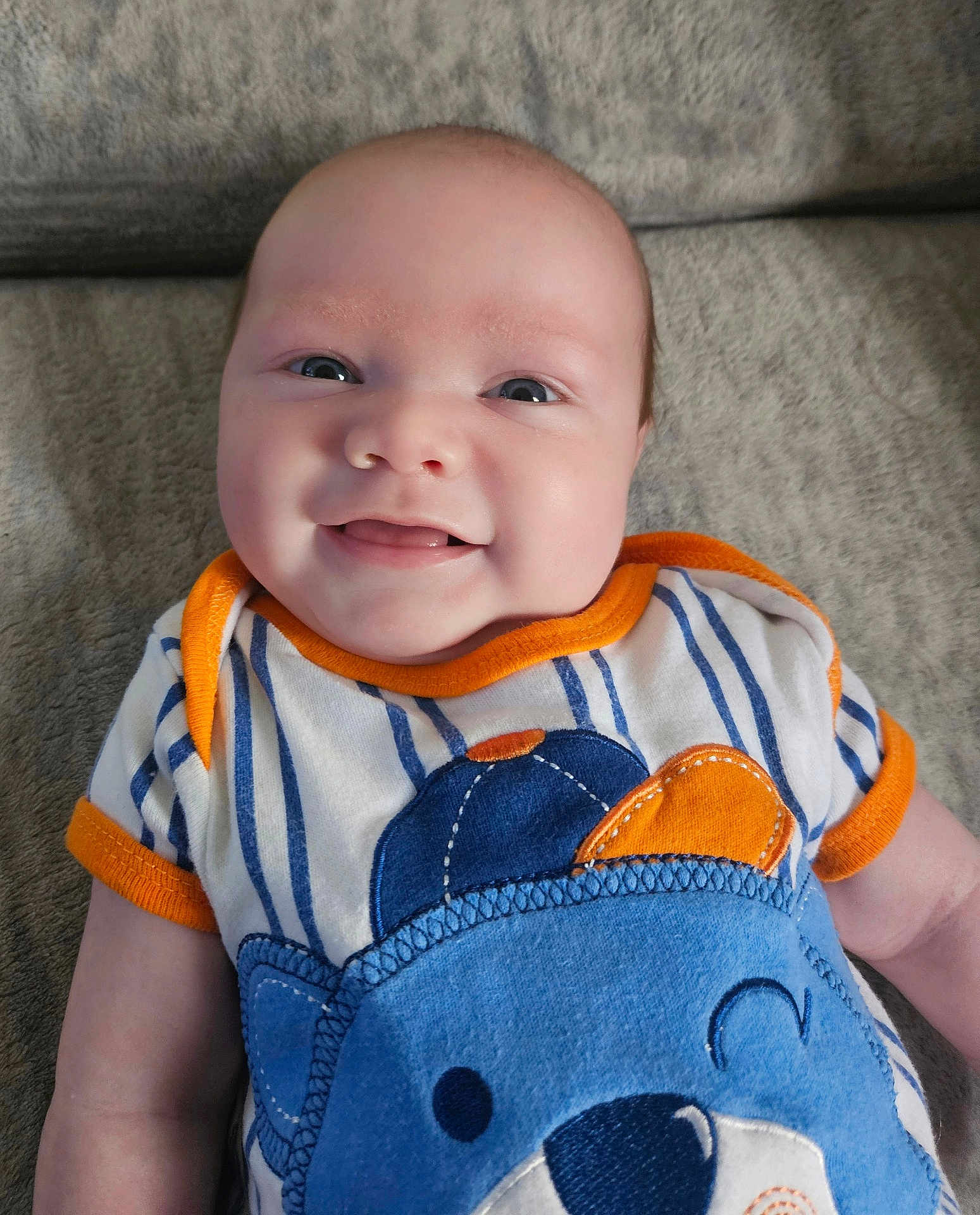 Dakota joined the competition — help win amazing prizes! baby, smiling, infant, face, clothing, striped, bear_design, blue, orange, happy, cute, lying_down, soft_blanket, child, portrait, head, skin, person, eyes, mouth