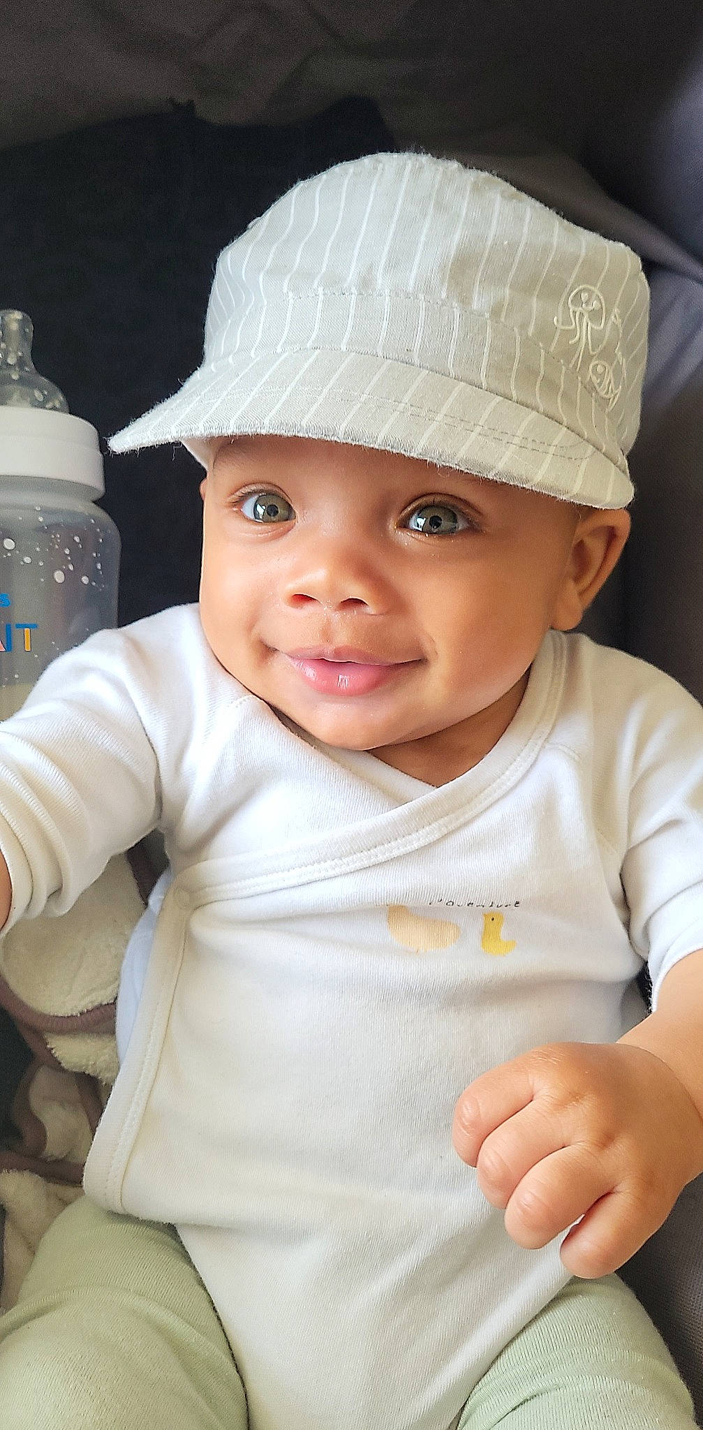 Keindrix Felix participe au concours pour gagner de l'argent avec cette photo : baby, baby_toddler_clothing, cap, cheek, clothing, eye, face, facial_expression, head, headgear, headwear, joy, light, lip, organ, person, plastic_bottle, product, skin, sleeve