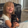 Onyx is registered to the contest to win money with this photo: affection, black_pug, blanket, bracelet, carpet, casual_clothing, child, cozy, cute, dog, girl, happy, home, indoor, pet, puppy, seated, smiling, vertical_blinds, young