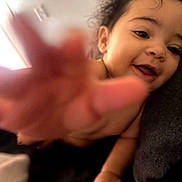 Asha is registered to the contest to win money with this photo: baby, candid, child, closeup, curly_hair, cute, expression, face, hand, happy, indoor, person, playful, portrait, reaching, skin, smile, toddler, warm, young