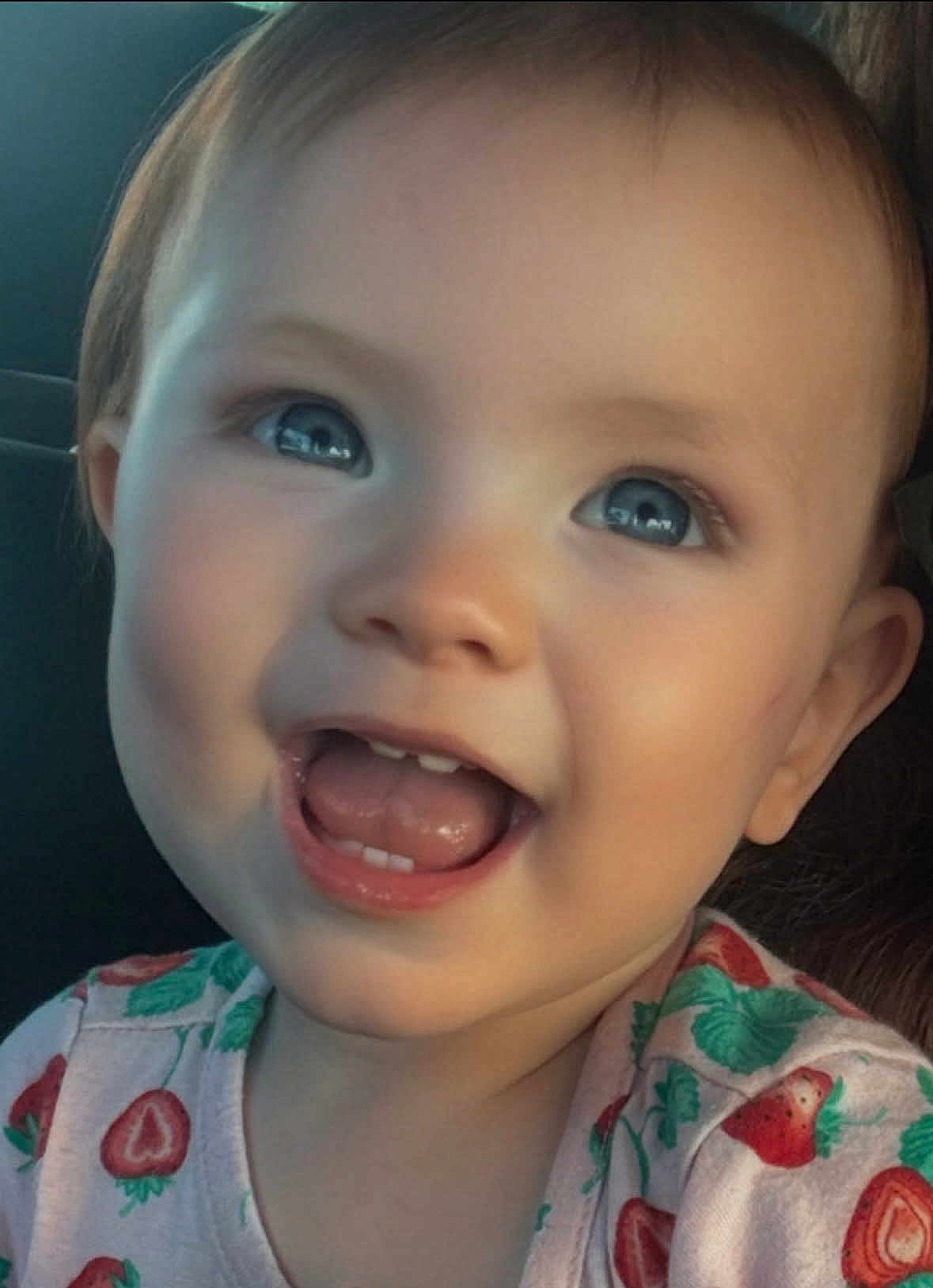 Alina is registered to the contest to win money with this photo: baby, child, smile, blue_eyes, face, teeth, tongue, strawberry_pattern, clothing, infant, happy, closeup, cute, person, young_child, mouth_open, skin, head, cheeks, indoors