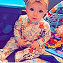 baby, child, onesie, headband, bow, toy, blanket, indoor, cute, infant, playmat, colorful, sitting, face, portrait, expression, animal_print, hand, footwear, soft