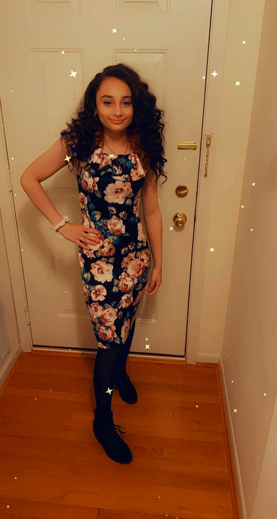 Kylie is registered to the contest to win money with this photo: black_hair, dress, face, fashion_design, flooring, formal_wear, high_heels, human_leg, joint, joy, knee, leg, long_hair, neck, person, sandal, shoe, sleeve, smile, thigh