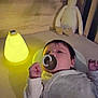baby, pacifier, night_light, plush_toy, duck, infant, sleepwear, bed, soft_lighting, wooden_background, toy, child, cute, indoors, relaxing, young_child, comfort, sleepy, blanket, cozy