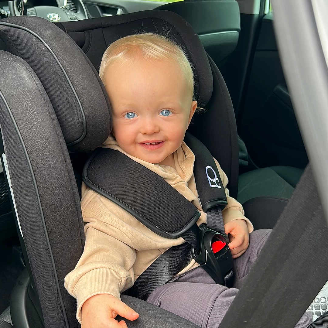 Jett is registered to the contest to win money with this photo: accessories, baby, belt, car, car_interior, carseat, clothing, coat, cushion, face, head, headrest, homedecor, jacket, person, photography, portrait, sitting, transportation, vehicle