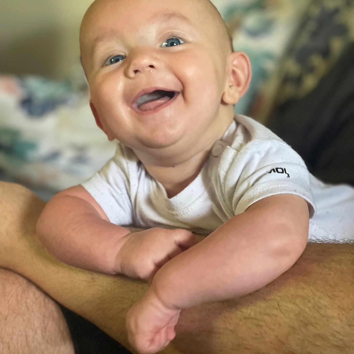 Rhys is registered to the contest to win money with this photo: baby, babylaughing, bodypart, clothing, face, happy, head, laughing, mouth, newborn, person, photography, portrait, sitting, smile, t_shirt, teeth