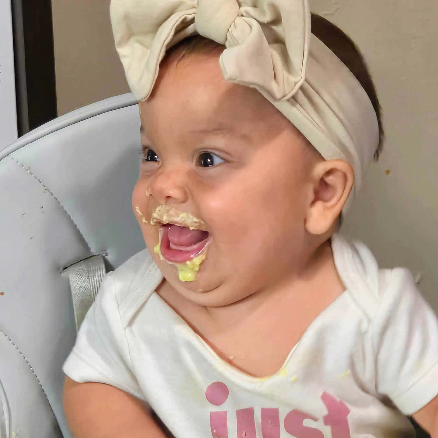Azul is registered to the contest to win money with this photo: baby, child, clothing, cream, cute, face, feeding, food, fun, hand, happy, headband, high_chair, indoor, infant, joy, messy, playful, smile, table