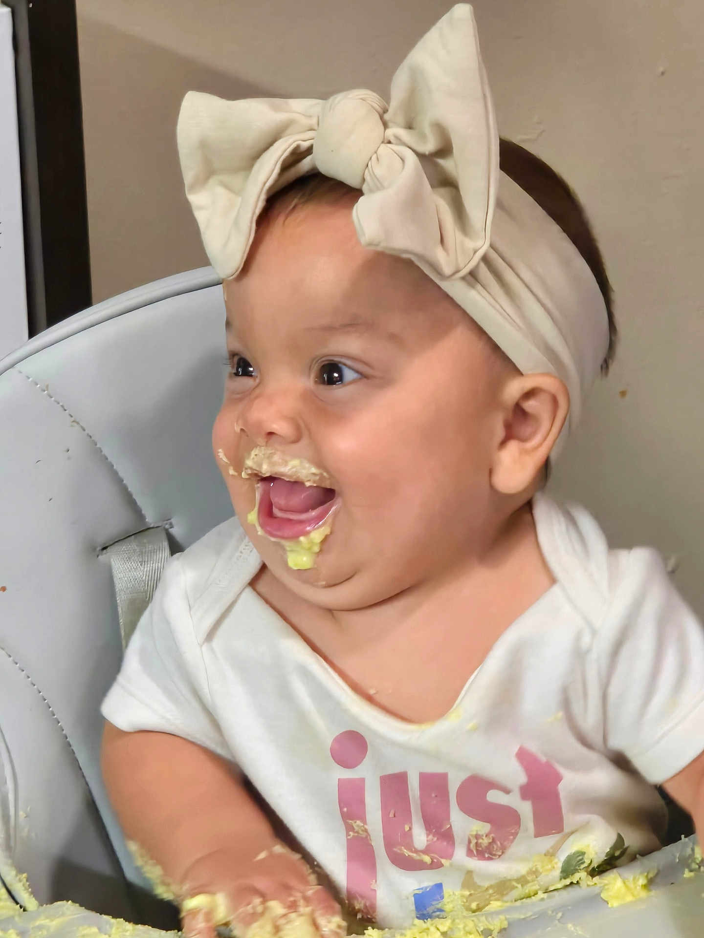 Azul is registered to the contest to win money with this photo: baby, messy, food, high_chair, headband, smile, happy, child, face, hand, clothing, indoor, feeding, cream, cute, infant, fun, playful, table, joy