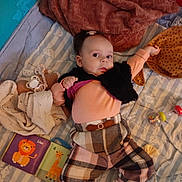 Cléophée a rejoint le concours — aidez-le/la à gagner de superbes lots ! baby, blanket, book, child, colorful, cozy, curious, cute, face, head, indoor, infant, lying_down, nursery, patterned, plaid_pants, shoes, soft_toy, sweater, toy