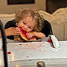 child, curly_hair, cute, eating, face, food, fruit, happy, high_chair, indoor, juice, kitchen, meal, messy, person, seat, snack_time, table, toddler, watermelon