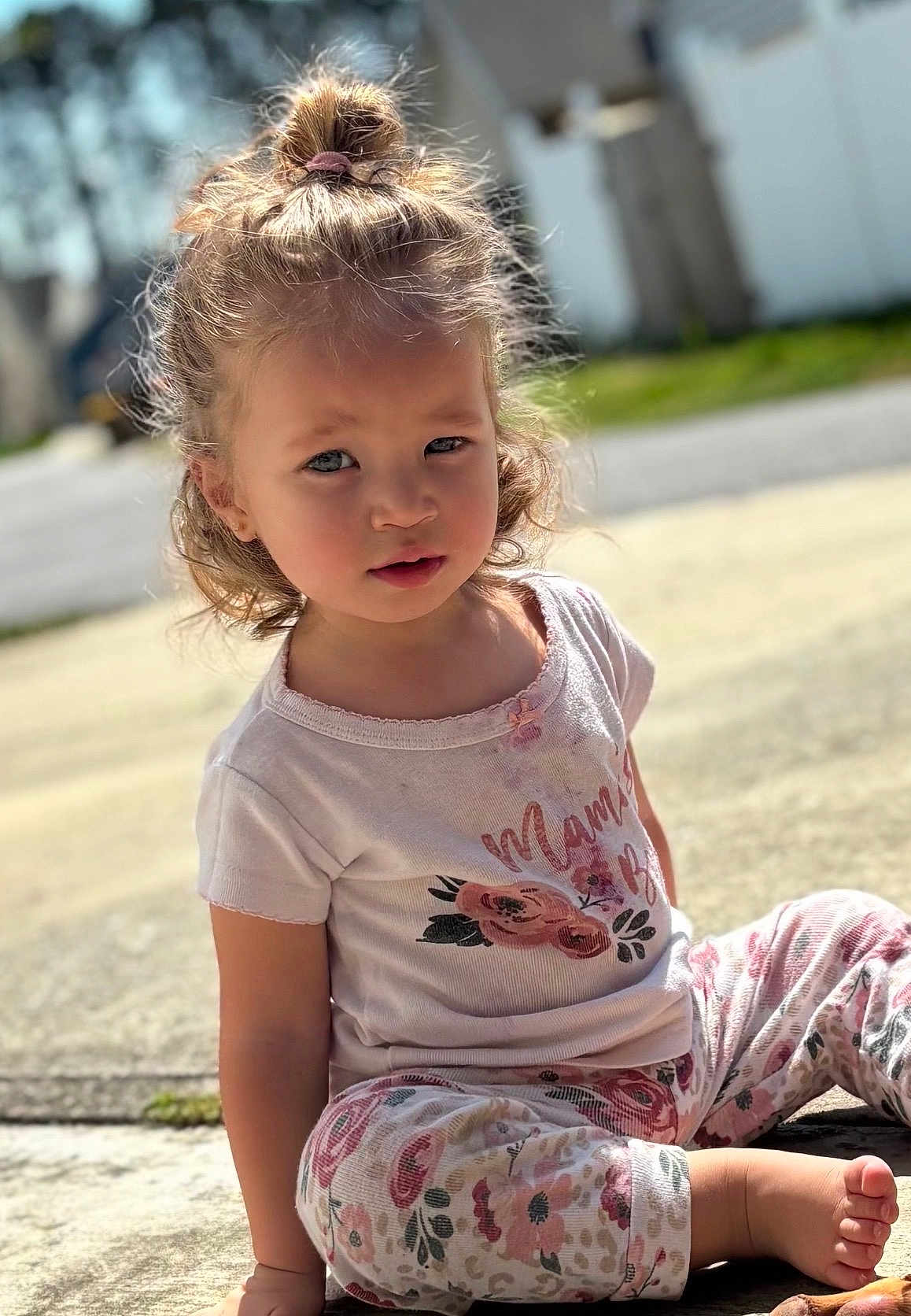Zoelle is registered to the contest to win money with this photo: child, toddler, girl, sitting, outdoors, sunlight, portrait, casual_clothing, floral_pattern, t-shirt, leggings, barefoot, curly_hair, topknot, expression, gaze, sidewalk, suburban, soft_lighting, depth_of_field