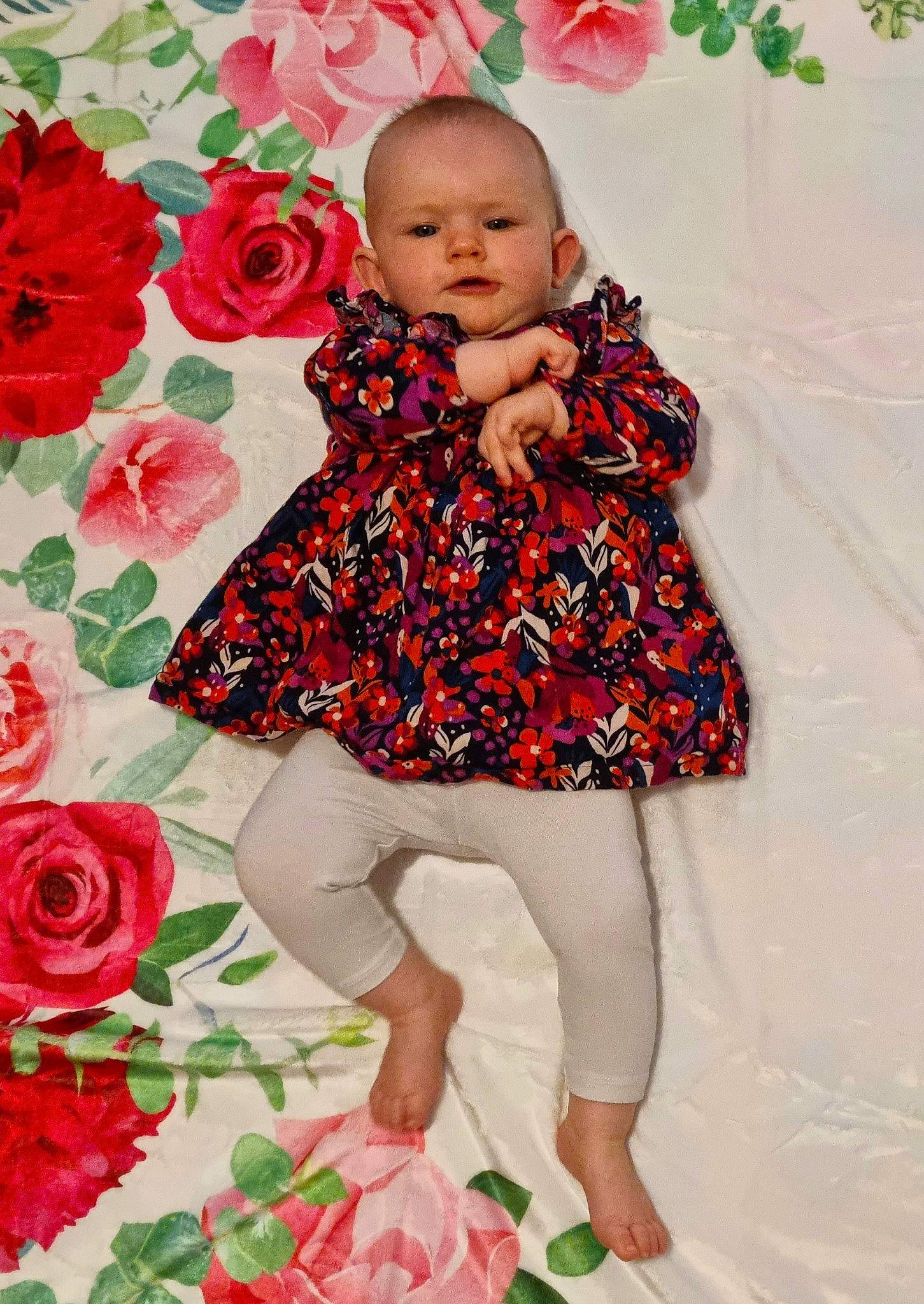 Léana a rejoint le concours — aidez-le/la à gagner de superbes lots ! baby_toddler_clothing, day_dress, dress, face, flower, green, happy, pattern, people_in_nature, person, petal, pink, plant, red, rose, skin, sleeve, standing, thigh, toddler