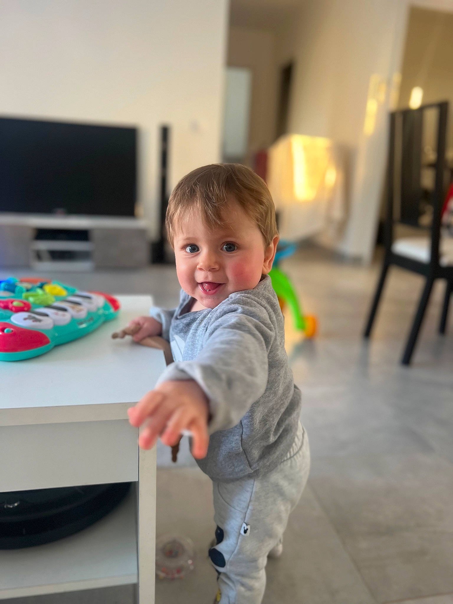 Mylann participe au concours pour gagner de l'argent avec cette photo : baby, baby_playing_with_toys, baby_toddler_clothing, child, desk, flooring, fun, gadget, happy, hardwood, input_device, peripheral, person, play, room, sitting, smile, t_shirt, table, toddler