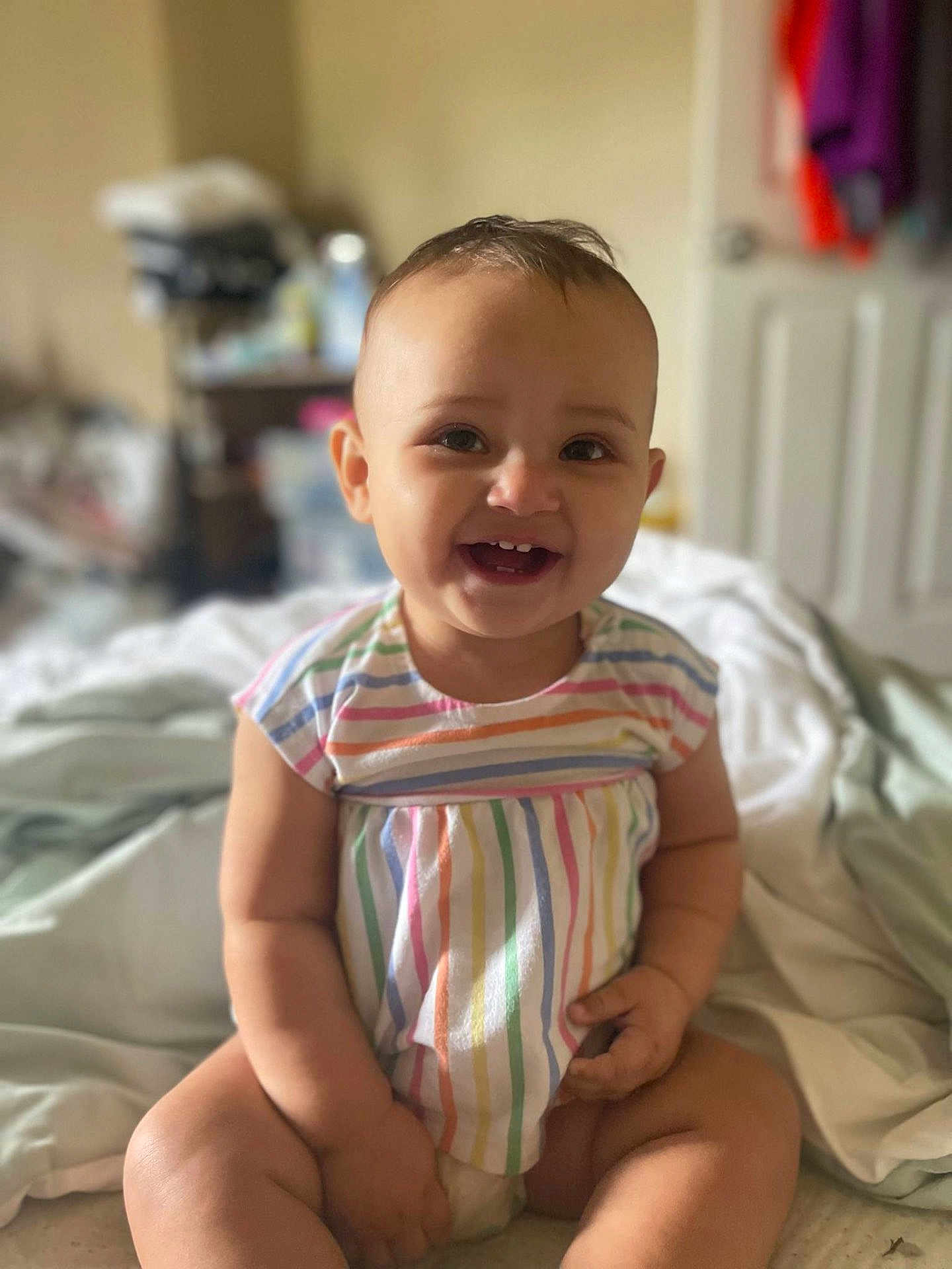 Ariyah is registered to the contest to win money with this photo: baby, child, smiling, sitting, indoors, bed, clothing, striped, happy, cute, infant, person, portrait, tooth, skin, face, head, chubby, toddler, room
