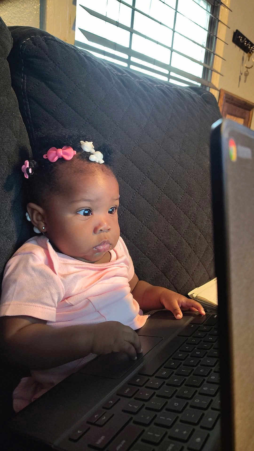Paris joined the competition — help win amazing prizes! baby, child, laptop, couch, hair_clips, pink_shirt, indoor, window, sunlight, typing, curly_hair, earrings, technology, focused, young_child, furniture, home, person, black_hair, cute