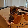 animal, bed, brown, cat, cozy, curious, cute, domestic_animal, ears, fabric, feline, indoor, notebook, orange, pet, plush_toy, resting, soft_toy, tabby_cat, whiskers