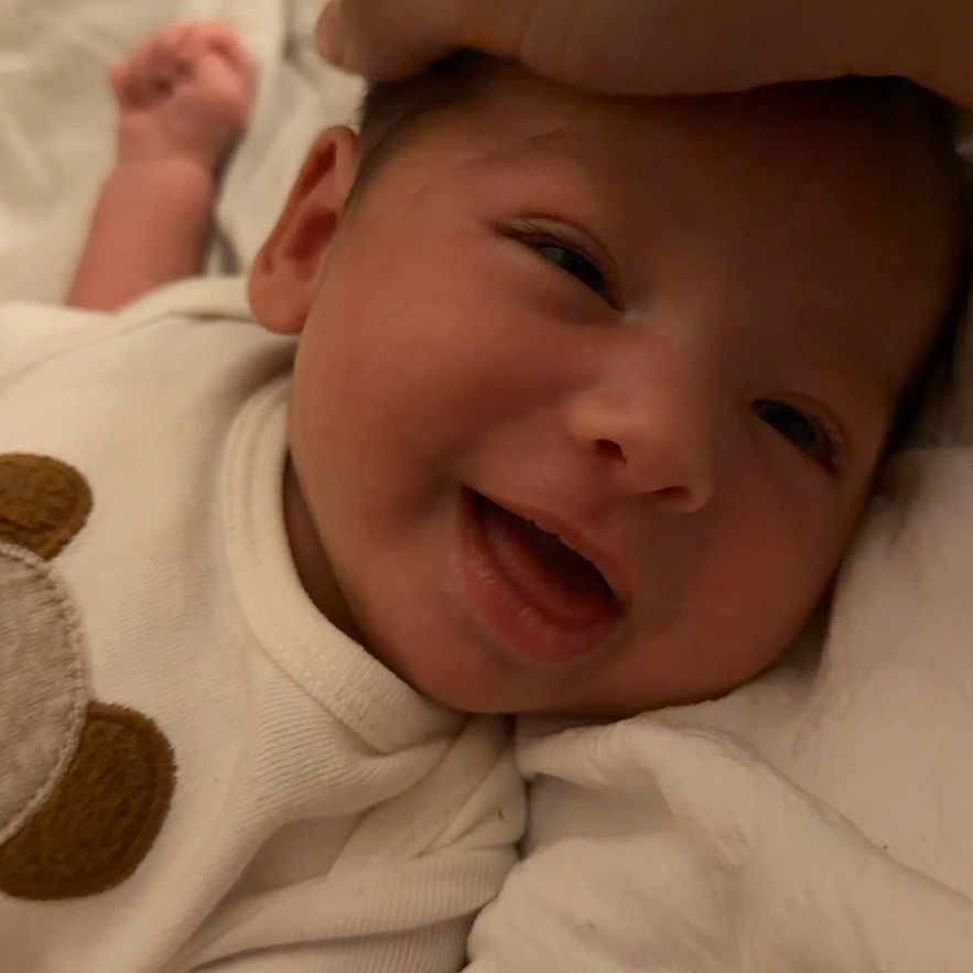 Victoria is registered to the contest to win money with this photo: baby, bear_patch, blanket, closeup, clothing, comfort, cozy, cute, expression, face, hand, happy, infant, lying_down, newborn, person, skin, smiling, soft, tender