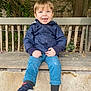 child, toddler, smiling, blue_eyes, jacket, pants, sneakers, bench, outdoor, tree, leaves, wood, stone, happy, person, casual_clothing, nature, daylight, cute, playful