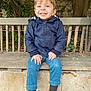 Malo participe au concours pour gagner de l'argent avec cette photo : child, toddler, smiling, blue_eyes, jacket, pants, shoes, bench, outdoor, nature, tree, leaves, stone_wall, happy, person, casual_clothing, sitting, footwear, daylight, cute