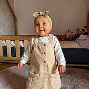 Gwendoline participe au concours pour gagner de l'argent avec cette photo : toddler, child, beige_dress, headband, carpet, wooden_crib, stuffed_animals, panda_toy, unicorn_toy, indoor, smiling, happy, curious, baby, person, clothing, floor, room, long_sleeve_shirt, footwear